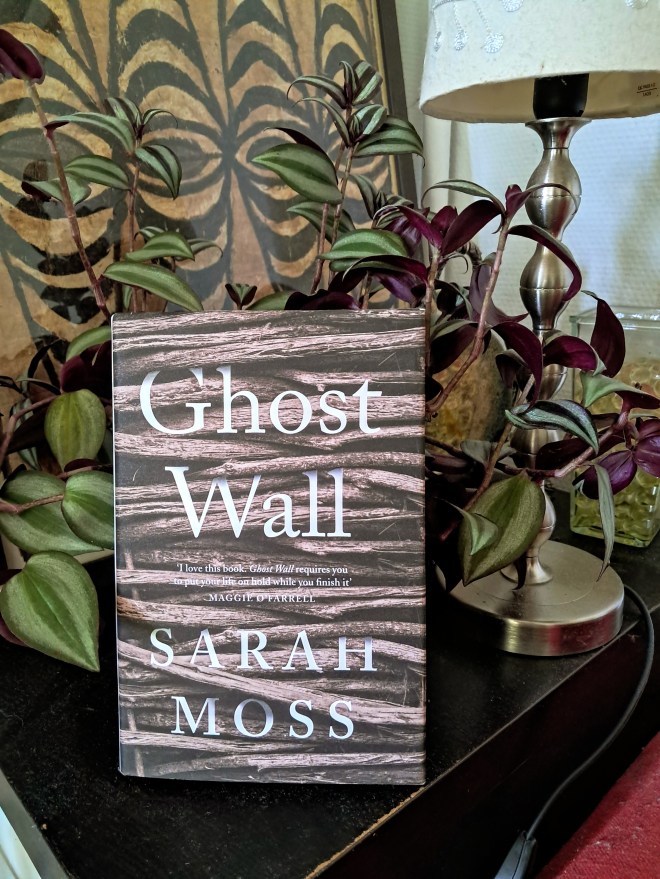 Book cover of novella Ghost Wall by Sarah Moss. The cover shows woven wood that might have been used to recreate an Iron Age hut.